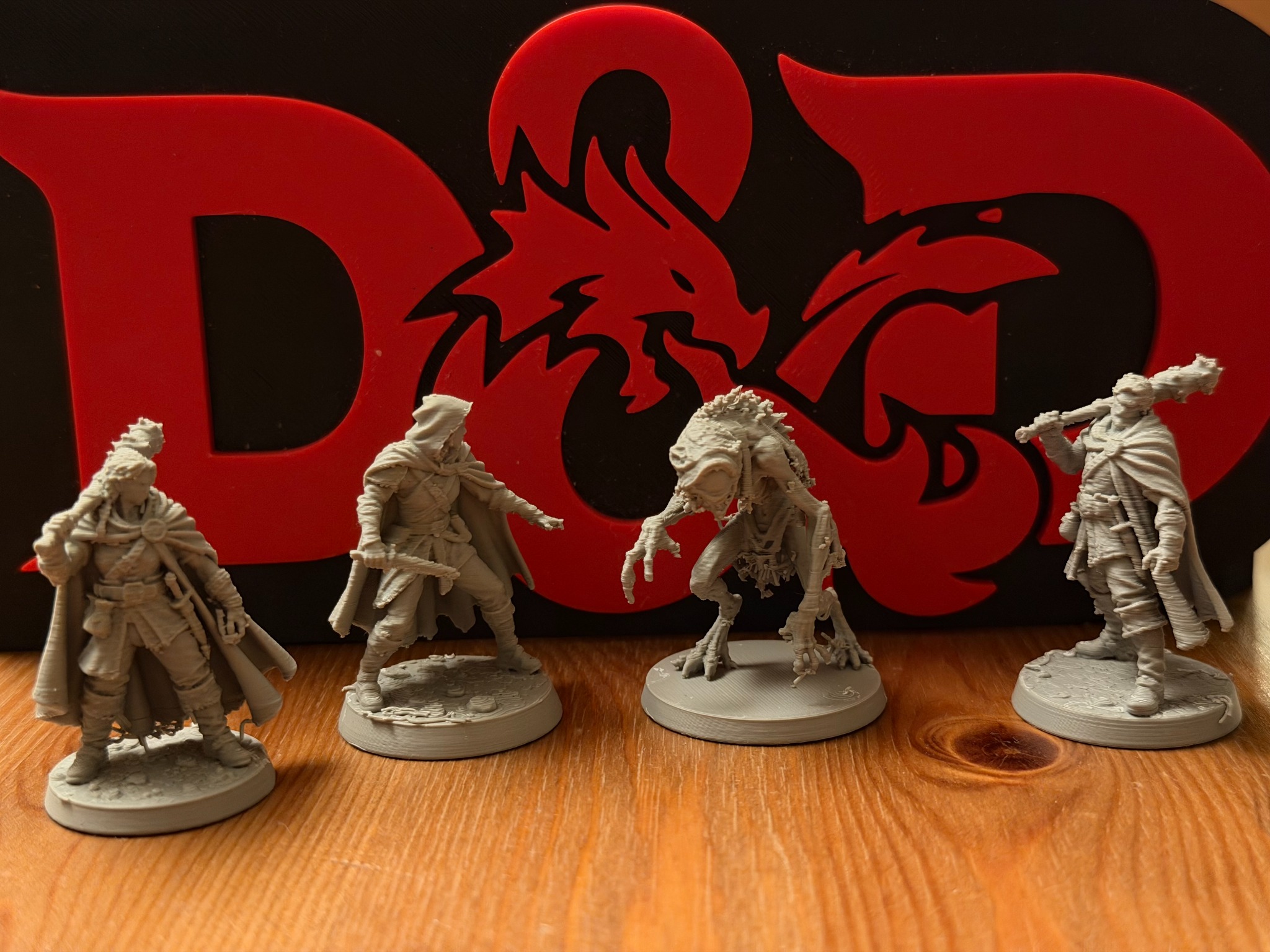 3D-miniaturen van de vier avonturiers uit onze Phandelver and Below-campagne voor het Dungeons and Dragons-logo